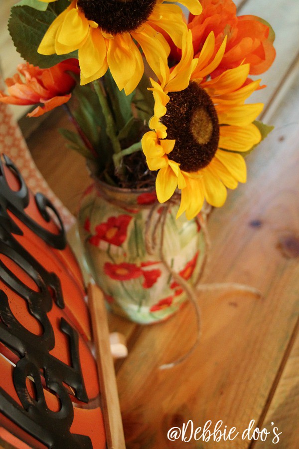 Faux sunflowers in a poppy vase
